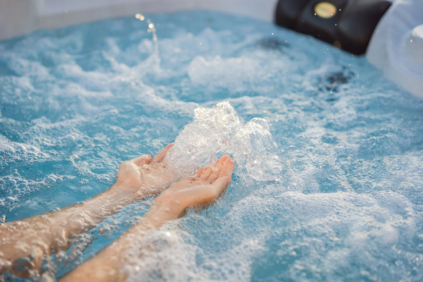 Hands playing with bubbling water in crystal-clear hot tub
